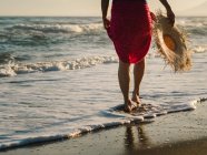 Vue de dos jambes coupées femelles marchant le long de la côte sous un soleil éclatant — Photo de stock
