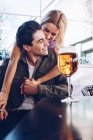 Jovem e alegre casal atraente desfrutando de bebida refrescante durante a caminhada na cidade — Fotografia de Stock