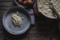 Da suddetto piatto di cottura al forno con pasta per torta di cottura su tagliere con uova su tavolo di legno — Foto stock