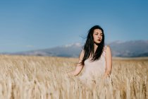 Beautiful Asian female looking away while standing on blurred background of meadow on windy day in nature — Stock Photo