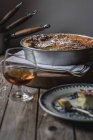 Cottage cheese baked pudding served on plate on towel and glass of cognac on wooden table — Stock Photo