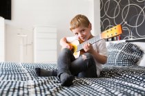 Giovane ragazzo biondo giocare giocattolo chitarra — Foto stock