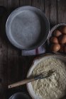 De cima assadeira com massa de farinha para cozinhar torta na tábua de corte com ovos na mesa de madeira — Fotografia de Stock