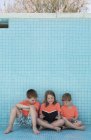 Children sitting in empty pool and reading book — Stock Photo