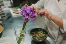 Salada de legumes com verde escuro em tigela de aço e mãos de chef verificando prato — Fotografia de Stock
