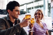 Cheerful young attractive couple enjoying refreshing drinks during walking in town — Stock Photo