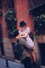 Vista lateral do jovem casal alegre em roupas casuais se divertindo durante o namoro ao ar livre — Fotografia de Stock