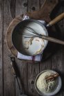De dessus plat de cuisson avec du lait et des écorces d'orange sur la planche à découper et bol de farine de maïs pour la cuisson sur fond en bois — Photo de stock