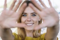 Jovem mulher de olhos azuis sorrindo e puxando as mãos para a câmera — Fotografia de Stock