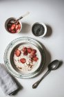 Flocons d'avoine servis dans un bol avec des fraises et des graines de chia en fond blanc — Photo de stock