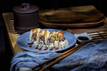 Аппетитные вкусные красочные суши с красным соусом и овощами за столом в ресторане — стоковое фото