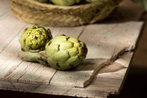 Fresh artichoke on old cracked wooden surface indoors — Stock Photo