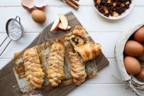Von oben köstliche frische Strudel mit süßen Äpfeln und Rosinen auf einer weißen Tischplatte neben Sieb und rohen Eiern — Stockfoto