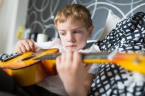 Young blonde boy playing toy guitar — Stock Photo
