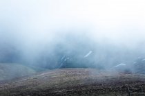 Estreita estrada asfáltica indo na encosta da montanha através de névoa espessa na natureza — Fotografia de Stock
