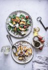 Da suddetto piatti con insalate gourmet fatte di pesche, cipolla rossa, formaggio, olio e pepe nero sulla tavola — Foto stock