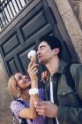 Вид сбоку на веселую молодую привлекательную женщину, кормящую парня мороженым на открытом воздухе — стоковое фото