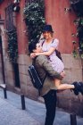 Fröhlicher junger Mann hat Spaß und trägt Freundin bei City-Date — Stockfoto