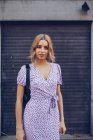 Ritratto di giovane donna attraente in abito in piedi sulla strada in posa e guardando in macchina fotografica — Foto stock