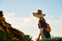Женщина-туристка в соломенной шляпе и рюкзаке, стоящих на природе — стоковое фото