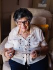 Seniorin in Bluse strickt Häkeln im Sessel — Stockfoto