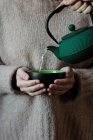 Pessoa derramando chá para xícara em mãos de mulher — Fotografia de Stock