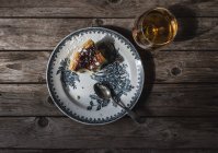 Vista superior de fatia de queijo cottage pudim assado servido na placa e vidro de conhaque na mesa de madeira — Fotografia de Stock