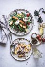 De dessus des assiettes avec des salades gastronomiques à base de pêches, oignon rouge, fromage, huile et poivre noir sur la table — Photo de stock