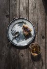 Вид зверху на шматочок сиру запечений пудинг, який подається на тарілці та склянці коньяку на дерев'яному столі — стокове фото