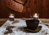 Подавать ароматный вкусный чай в чашке глины чайник и сладкие даты на белом подносе украшены листьями чая на деревянном фоне — стоковое фото