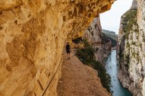 Vista trasera de un hombre irreconocible caminando a través de una garganta cerca de un río - foto de stock