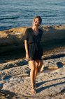 Jovem mulher atraente desfrutando de sol com olhos fechados na praia e segurando chapéu — Fotografia de Stock