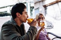 Allegro giovane coppia attraente godendo bevande rinfrescanti durante data in città — Foto stock