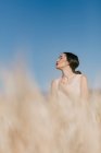 Beautiful Asian female looking away while standing on blurred background of meadow on windy day in nature — Stock Photo