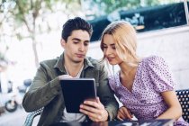 Весела молода приваблива пара використовує цифровий планшет на відкритому повітрі в місті — стокове фото