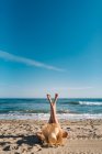 Розслаблена жінка насолоджується хорошою погодою, лежачи з піднятими схрещеними ногами вгору на піщаному пляжі в яскравий день — стокове фото