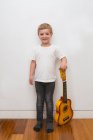 Молодой блондин играет на игрушечной гитаре — стоковое фото
