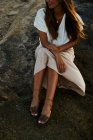 Jovem modelo feminino sentado na rocha e olhando para longe — Fotografia de Stock