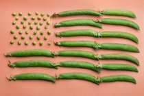 Colocação plana da bandeira dos EUA feita com ervilhas e vagens de ervilha no fundo do salmão — Fotografia de Stock
