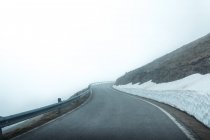Асфальтовая дорога через заснеженную горную террасу в туманный день — стоковое фото