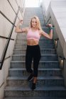 Молода блондинка біла жінка згинає м'язи зі спортивним одягом на відкритому повітрі — стокове фото