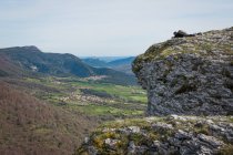 Vista lateral del hombre irreconocible con mochila en la montaña y vista pintoresca de campos y colinas. - foto de stock
