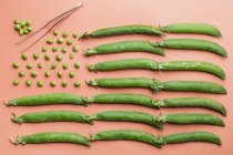 Colocación plana de la bandera de EE.UU. hecha con guisantes y vainas de guisantes sobre fondo salmón - foto de stock
