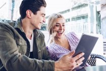 Fröhliches junges attraktives Paar nutzt digitales Tablet im Freien in der Stadt — Stockfoto