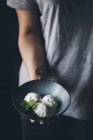 Female hand holding bowl with stracciatella ice cream balls decorated with mint leaves — Stock Photo