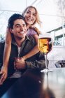 Jovem e alegre casal atraente desfrutando de bebida refrescante durante a caminhada na cidade — Fotografia de Stock