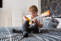 Молодой блондин играет на игрушечной гитаре — стоковое фото