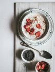 Served oatmeal in bowl with strawberries and chia seeds in white background — Stock Photo