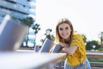Portrait of young smiling blonde woman looking at camera leaning on handrail — Stock Photo