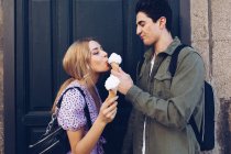 Веселая молодая привлекательная женщина и ее парень едят мороженое на открытом воздухе — стоковое фото